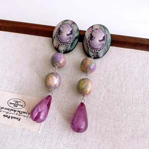 Detailed shot of vintage cameo earrings with purple teardrop pendants and marble beads