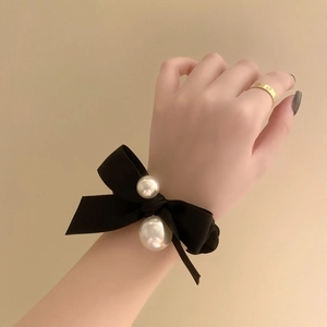 Elegant black velvet bow hair scrunchie with large white pearls shown on a model