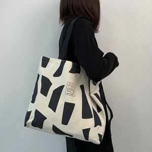 Detail of canvas tote bag with black geometric patterns and Good Student print