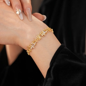 Détail d'un bracelet à maillons dorés orné de pierres de zircon claires sur un mannequin