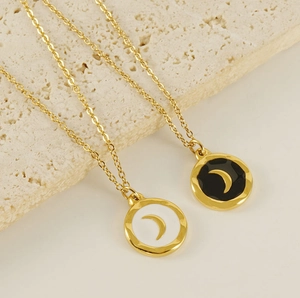 Detail of 18K gold plated celestial pendants with black and white enamel moon on stone