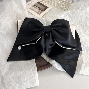 Detailed view of elegant black and white satin bow hair claw clip with pearl accents