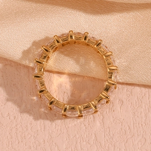 Macro detail of 18K gold plated ring with rectangle-cut square zircons on silk background