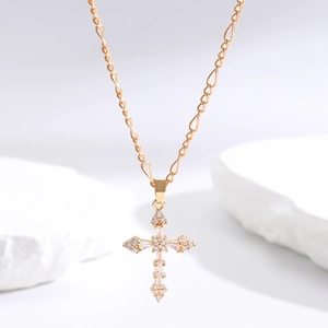 Close-up of golden cross necklace with cubic zirconia on white stone textures