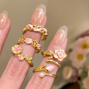 Close-up of 18k gold plated flower rings with pink enamel and pearl details