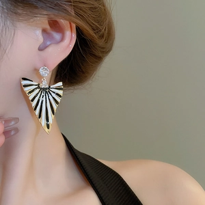 Gros plan de boucles d'oreilles géométriques émaillées avec cristaux portées par un modèle