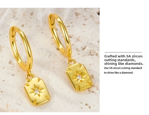 Macro detail of gold-plated earrings with rectangular starburst pendant and 5A zircon