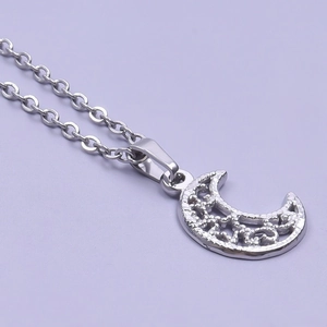 Macro view of silver crescent moon pendant with hollow design on a delicate cable chain