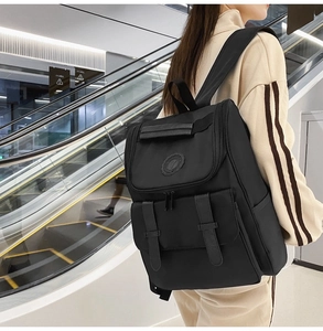 Rear view of a model wearing a large black nylon backpack with multiple buckled pockets
