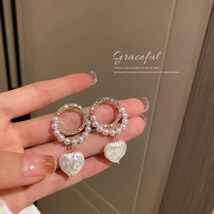 Elegant gold earrings with sparkling rhinestones, circular pearls and a heart pendant