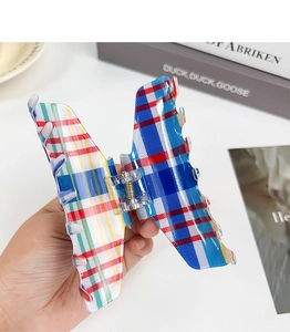 Detail of butterfly hair claw clip with red white blue plaid pattern held in hand