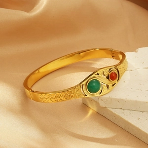 Detail of vintage gold bangle with hollow patterns and green and red bead inlays