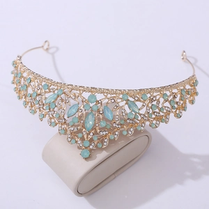 Detailed view of Baroque gold crown featuring light blue rhinestones and floral leaf patterns