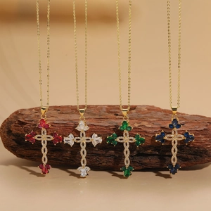 Detailed view of cross pendants with red, white, green, and blue stones on gold chains