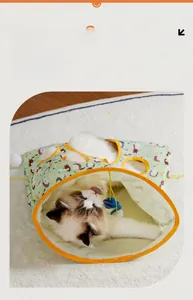 Detail of cartoon printed cat tunnel bed featuring a hanging toy and a cat playing inside