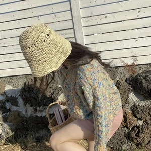 Minimalist beige hollow woven straw bucket hat styled with a colorful knit sweater
