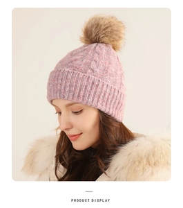 Close-up of pink knit beanie with ribbed cuff and fluffy faux fur pom-pom detail
