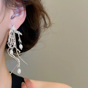 Detail of liquid metal tassel earrings featuring three elegant white teardrop pearls