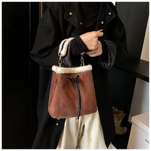 Close-up of brown suede bucket bag featuring white faux shearling trim and drawstring