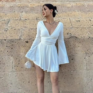 Detail of white mini dress featuring deep V-neck, flared sleeves, and pleated waist design