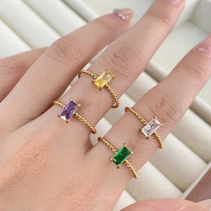 Detailed macro view of four sparkling rectangular colored gemstone rings on twisted bands