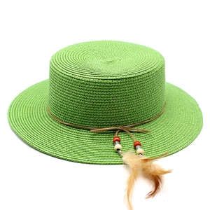 Detail of green straw boater hat with decorative brown cord beads and feathers