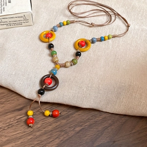 Detailed close-up of handmade ethnic ceramic bead necklace with wooden rings on linen cloth