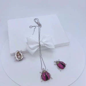 Detail of ladybug jewelry set with pink and black stones in a white gift box