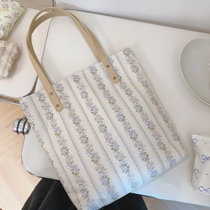 Detailed top view of floral canvas tote bag with light purple stripes and leather handles