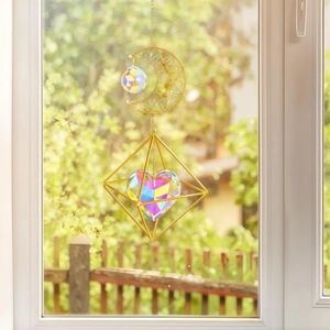 Detail of moon and heart crystal suncatcher with golden metal frame reflecting light
