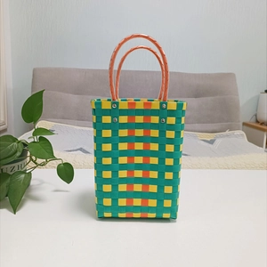 Detail of colorful woven basket bag with orange ring handles and silver metal rivets