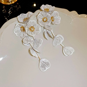 Vue macro de boucles d'oreilles fleurs plissées blanches avec détails dorés sur plateau