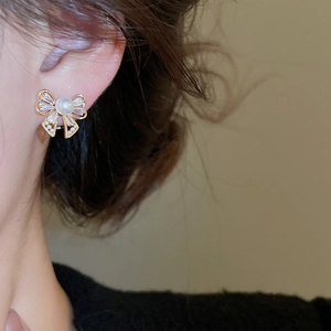 Close-up of bowknot pearl earrings with zircon inlay worn by model in vintage style