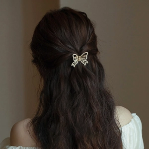 Elegant gold bow hair claw with pearls on long wavy hair, French vintage style accessory