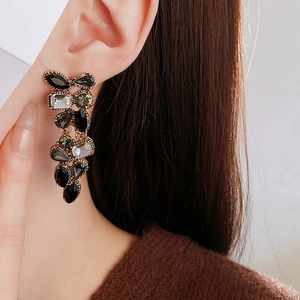 Détail de longues boucles d'oreilles à pompons avec pierres multicolores sur un mannequin
