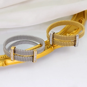 Detail of gold and silver mesh bangles with zircon buckles on white silk fabric