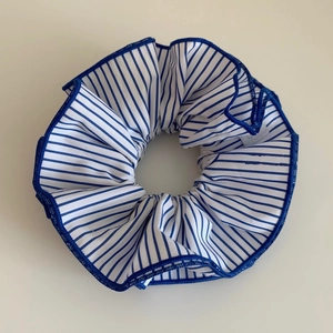 Détail d'un chouchou en tissu à rayures bleues et blanches avec bordure bleu foncé