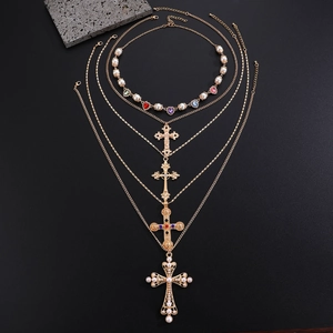 Detail of layered gold necklace featuring pearl accents and multi-color crystal crosses