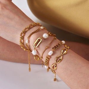 Close-up of stacked 18K gold plated titanium bracelets featuring natural freshwater pearls