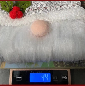 Weight measurement of a knitted Christmas gnome gift bag showing 44g on a digital scale