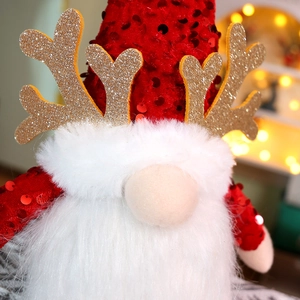 Close-up of a Christmas gnome doll with red sequin hat, golden antlers, and white faux fur beard