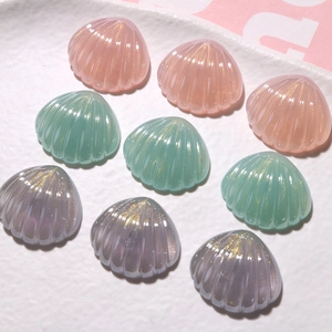 Dettaglio di ciondoli a conchiglia in resina glitterata rosa, verde e viola