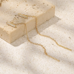 Detail of gold S925 silver thread earrings with square diamond studs on beige stone