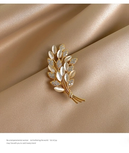 Detailed close-up of golden wheat brooch with opals on champagne satin fabric