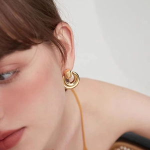 Close-up of model wearing chunky 18K gold plated hoop earrings with polished metal finish