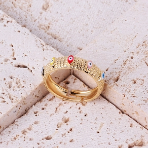 Macro detail of gold adjustable ring with colorful enamel evil eye charms on stone