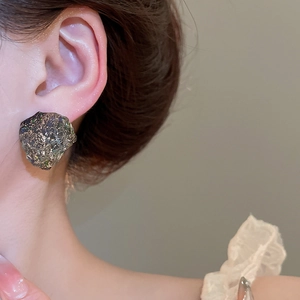 Close-up of irregular textured resin earrings with metallic iridescent finish on model