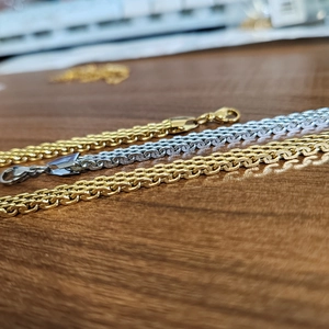 Bracelets à mailles plates en acier doré et argenté présentés sur du bois