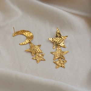 Macro detailed view of gold-plated asymmetric star and moon textured dangle earrings