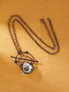 Detail van vintage bronzen hanger met witte kristaldruzy en maanastrologie-motieven